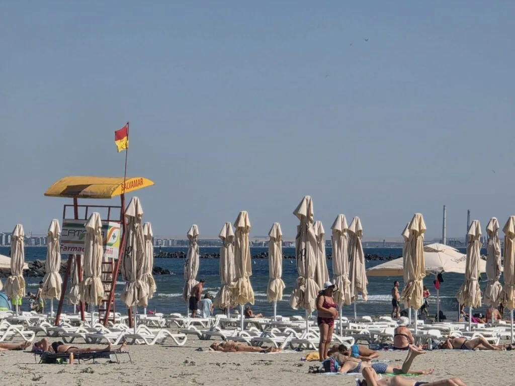 Plajă cu umbrele și turiști pe litoralul Mării Negre.