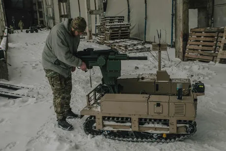 Un soldat pregătește un robot terestru pentru misiuni în condiții de iarnă.