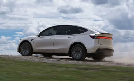 Un vehicul Tesla Model Y pe un drum de țară, sub un cer noros.