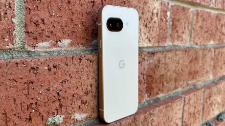 Un telefon Pixel 10a pe un zid de cărămidă, cu un design elegant.
