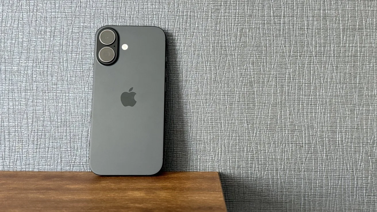 iPhone 16 pe o masă, cu un fundal texturat gri.