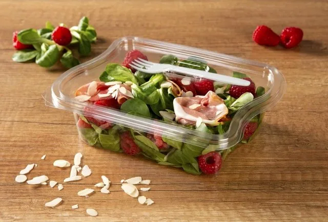 Ambalaj transparent pentru salată, cu ingrediente proaspete și furculiță.