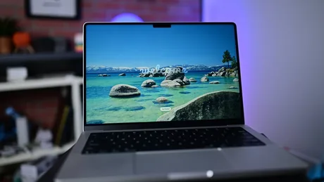 Laptop cu ecran OLED, pe fundal de peisaj natural, pregătit pentru utilizare.