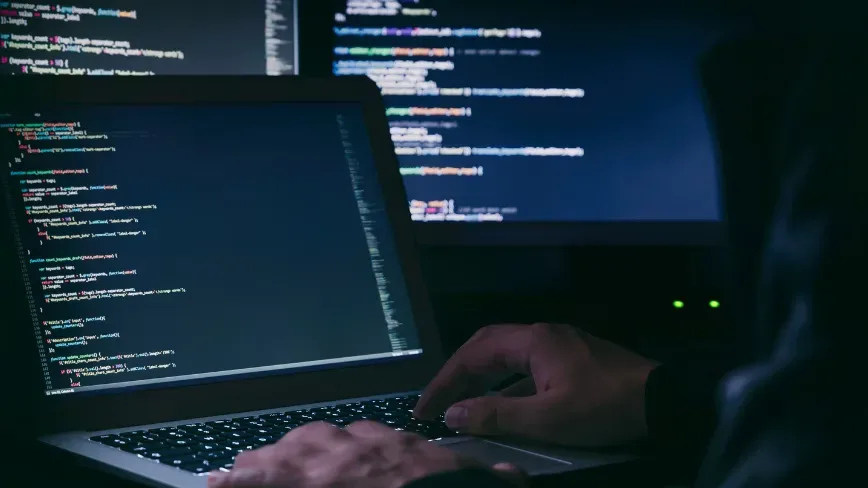 Un laptop cu cod sursă pe ecran, utilizat în atacuri cibernetice.