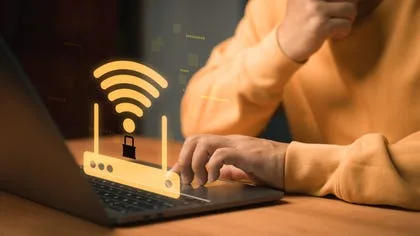 Un utilizator interacționează cu un laptop, având un simbol Wi-Fi în față.