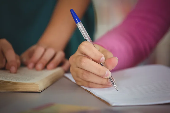 Un elev scrie într-un caiet, evidențiind importanța educației.