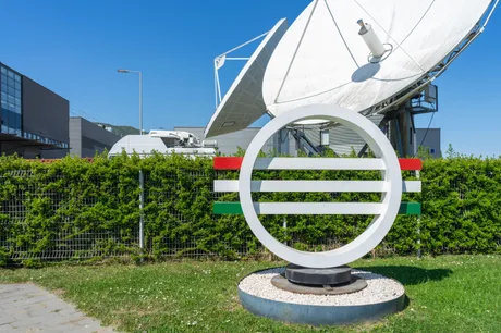 Logo-ul televiziunii publice din Ungaria, cu antene satelit în fundal.