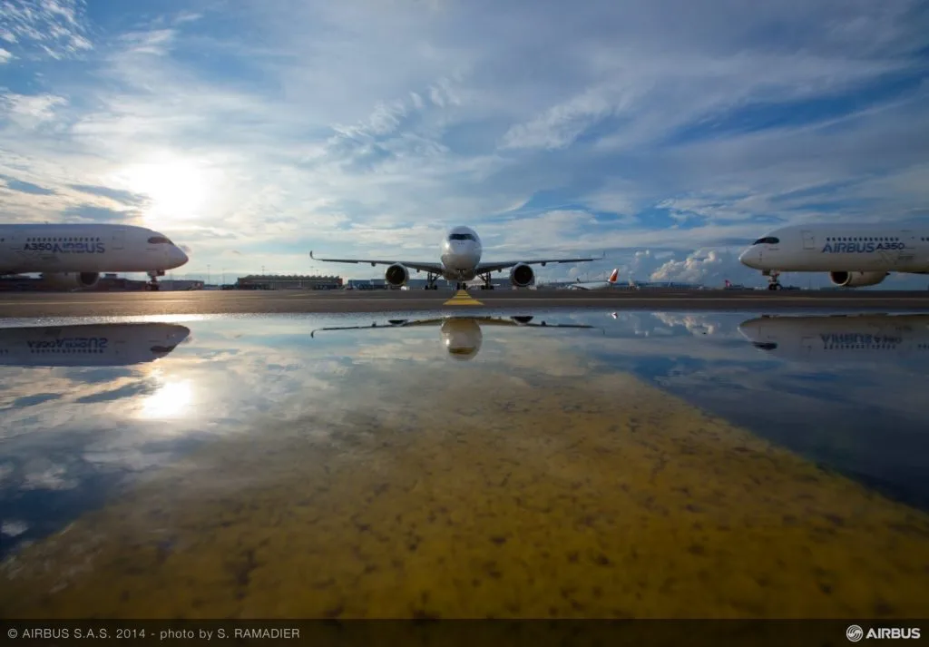 Avioane parcate pe pistă, reflectând cerul senin.