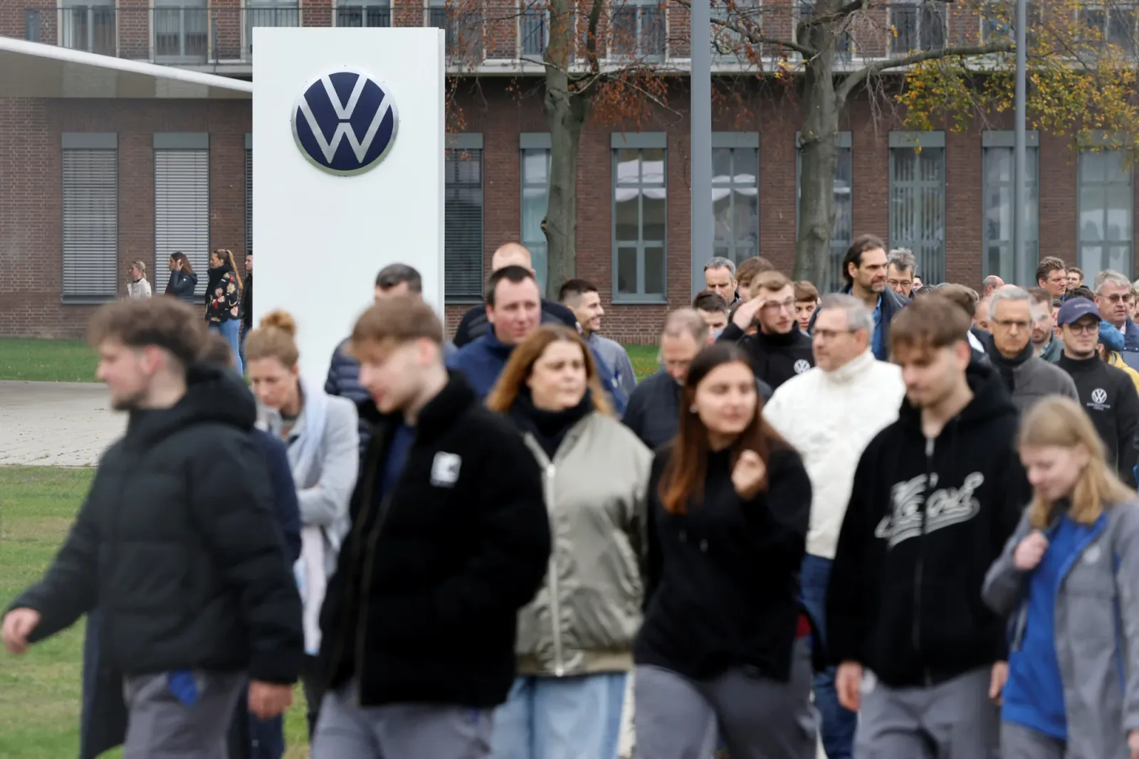 Angajați ai Volkswagen merg spre birou, discutând despre viitorul vehiculelor electrice.