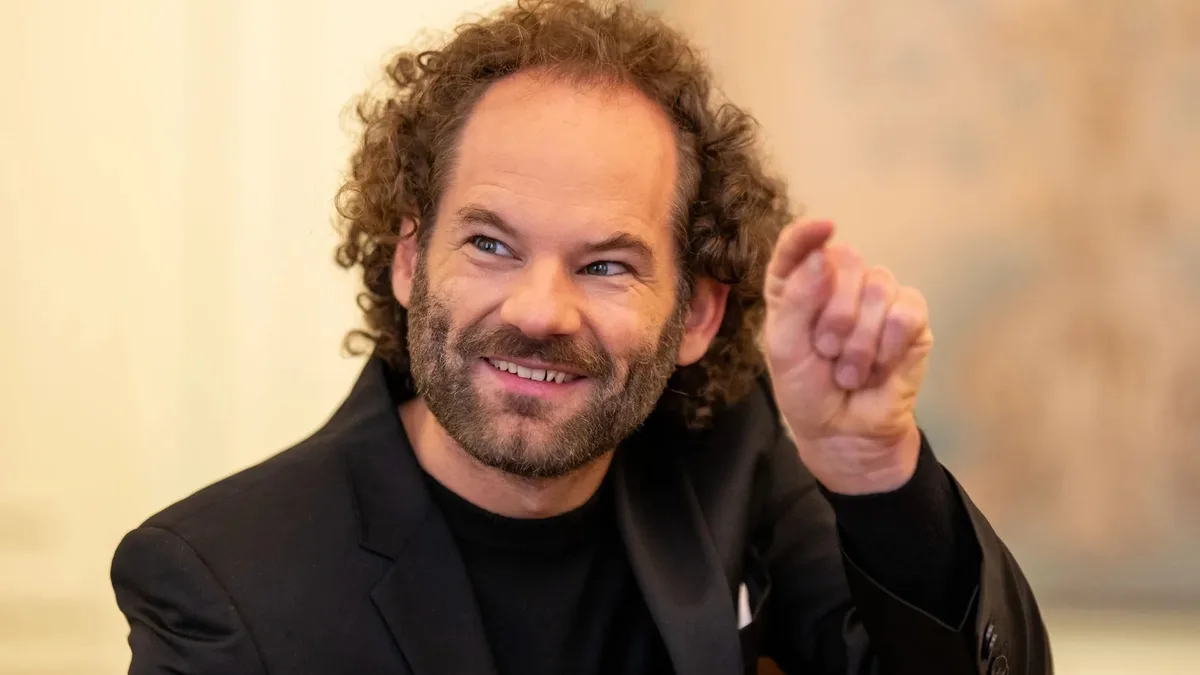 Comediantul Maxi Schafroth zâmbind în timpul unei discuții.