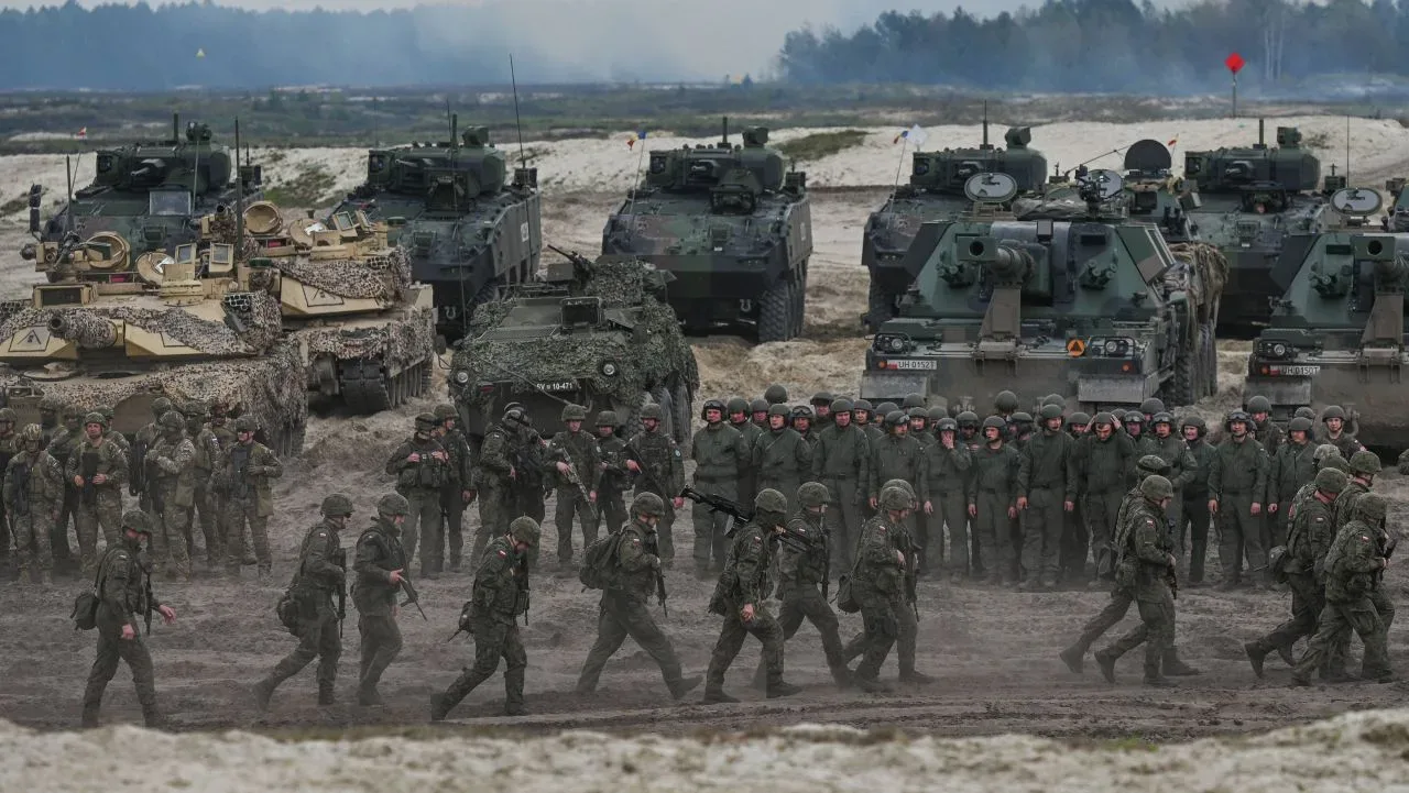 Soldați și vehicule militare în acțiune pe terenul de exerciții.