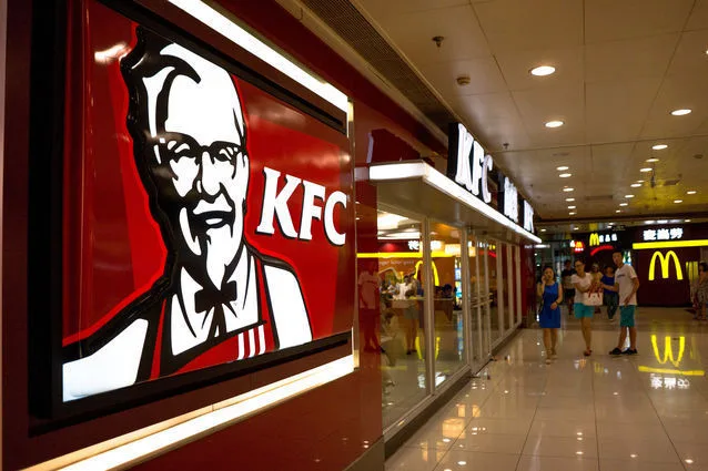 Logo KFC într-un restaurant, cu clienți în fundal.